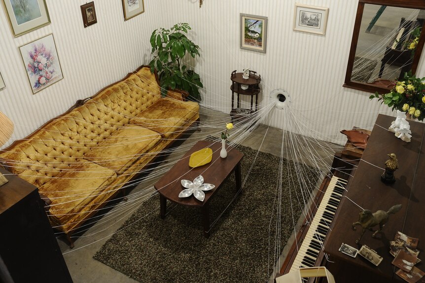 A living room with items connected by string leading to a wall portal.