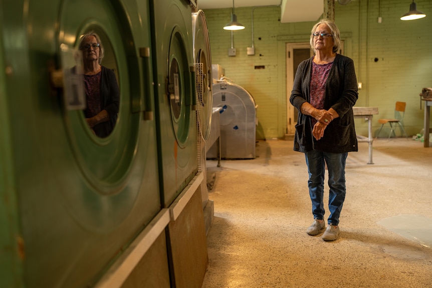 Woman standing in a room with old washing machines.