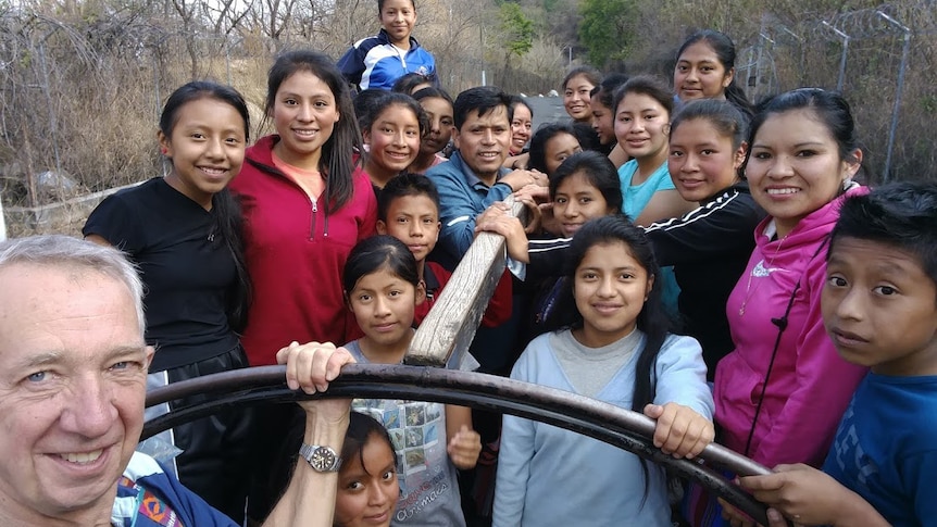 An older man with a group of Guatemalan people on the back of a truck.