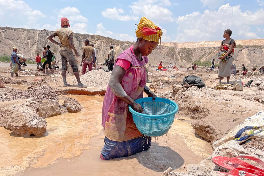 A woman wades in a pool of dirty water.