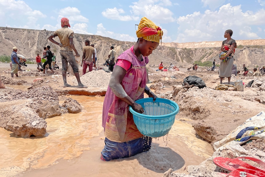 A woman wades in a pool of dirty water.