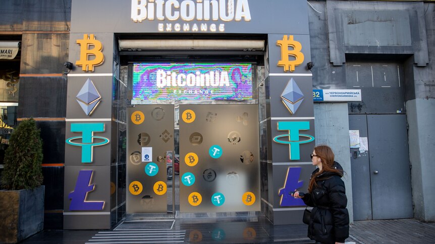 People walk past a shopfront reading BitcoinUA Exchange