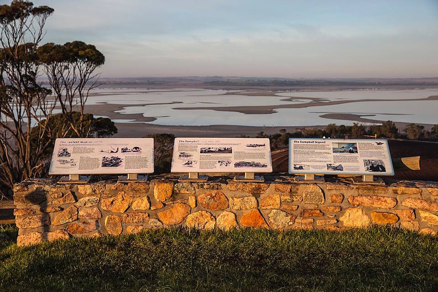 A row of plaques overlooking a lake.