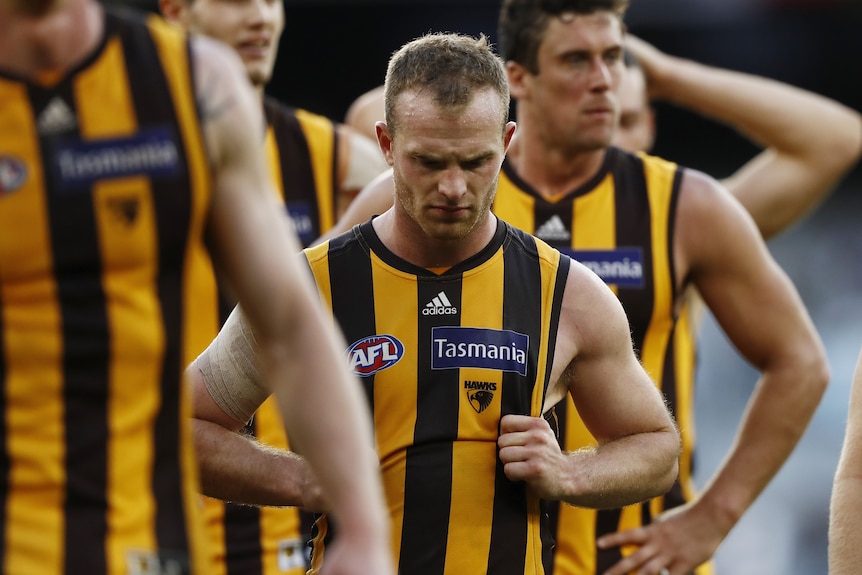 A Hawthorn AFl player walks with his head down after losing a game.