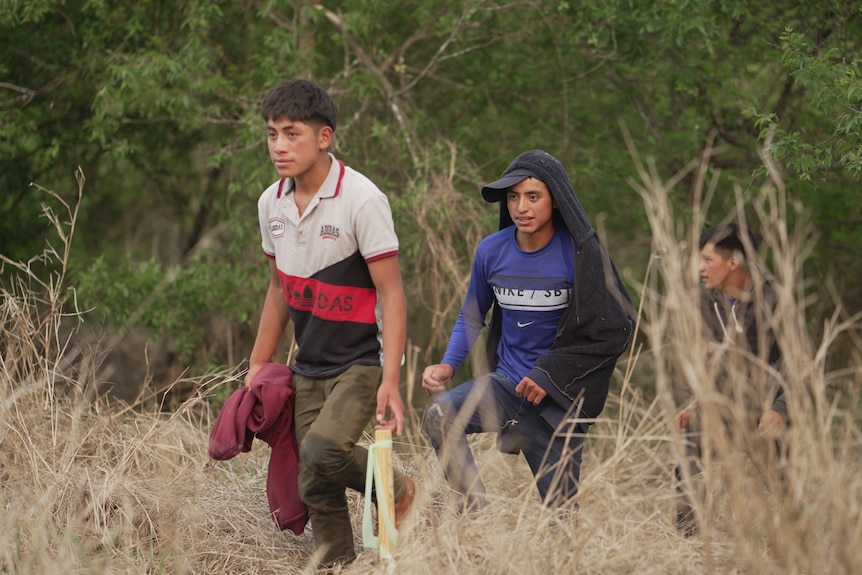 Three teenage boys walk up a hill.