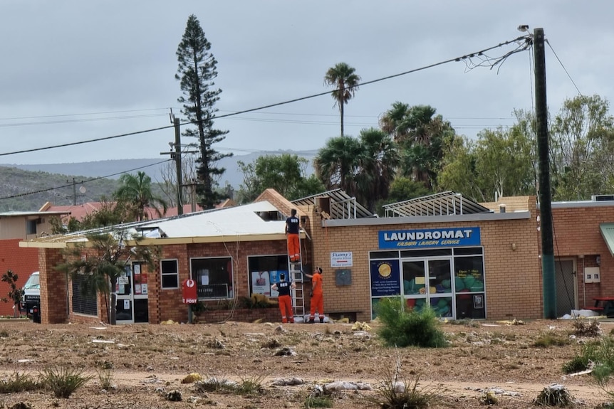 SES workers assess roof of Kalbarri shop damaged by Cyclone Seroja.