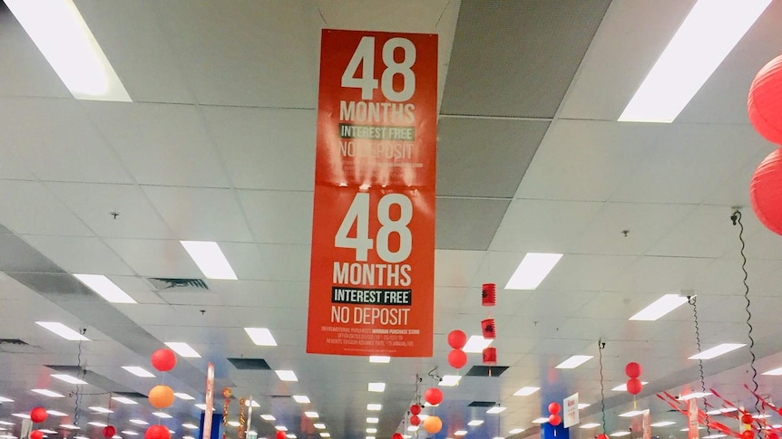 A red sign hanging from the roof of a Bing Lee store advertising 48 months interest free.