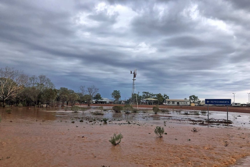 Brown flood water in foreground with buildings in the background.