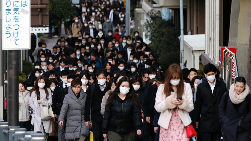 People wear masks as they commute during the morning rush hour in Tokyo.