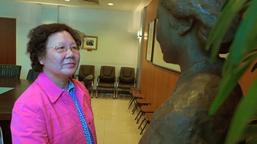 A woman looks at a statue of her former school principal.