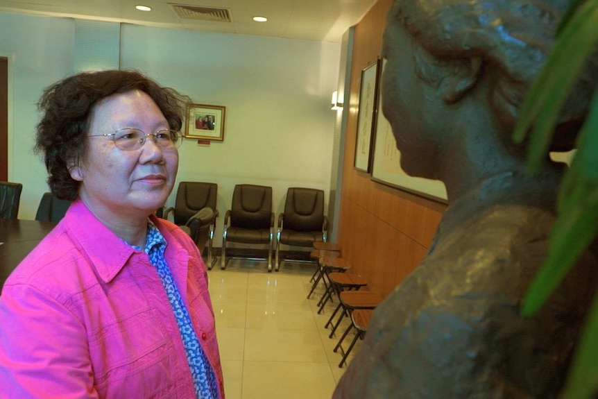 A woman looks at a statue of her former school principal.