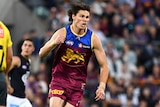 A Brisbane Lions forward runs back with his fists pumped in celebration after kicking a goal. 