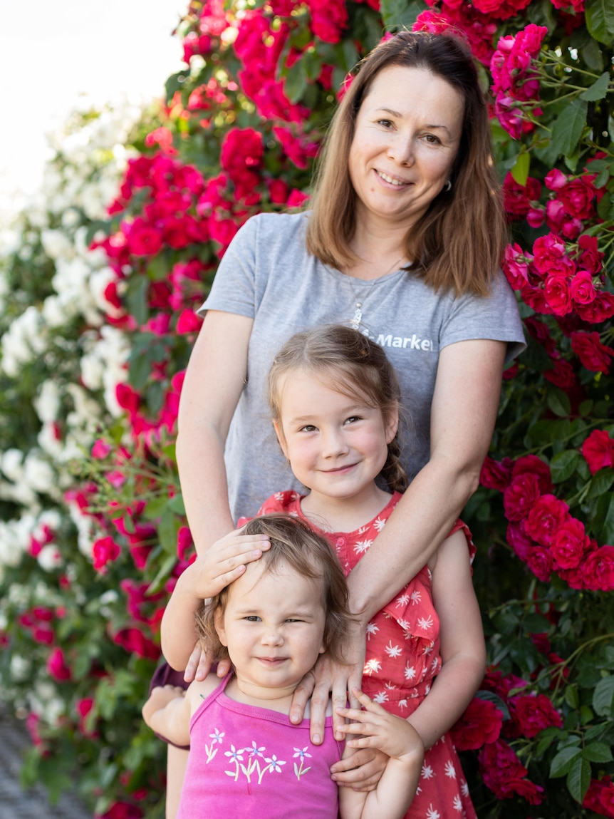 A woman and her two children in a garden.