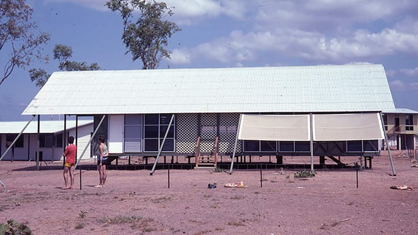 A coloured archival photo of tropical housing in Darwin.