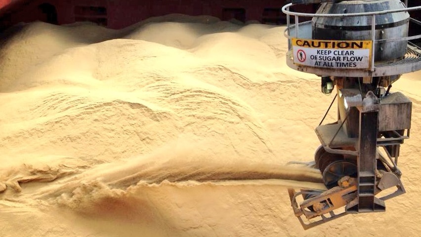 A machine pours sugar into a cargo hold.