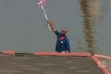 Call for help ... a man waves a flag from his rooftop to attract rescuers