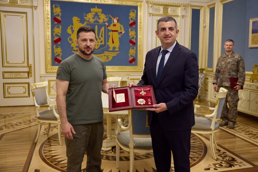 Volodymyr Zelenskyy presents a medal to a man in a suit 