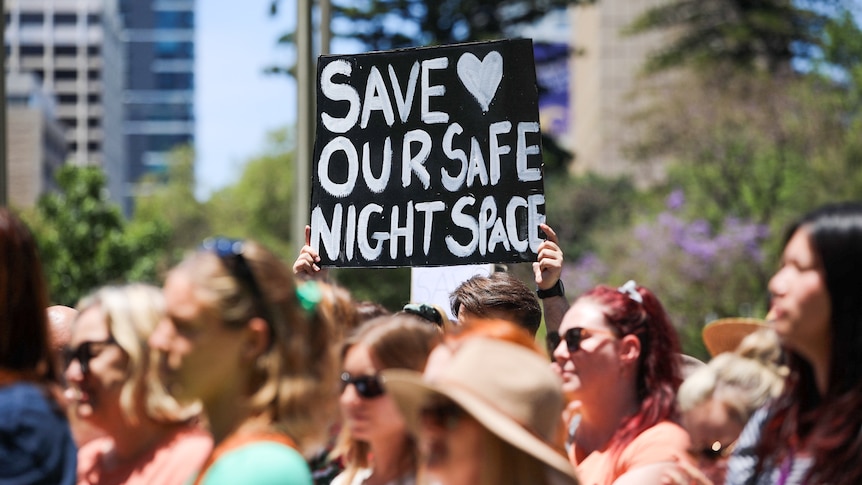 A protester holds a sign which says, Save Our Night Space.