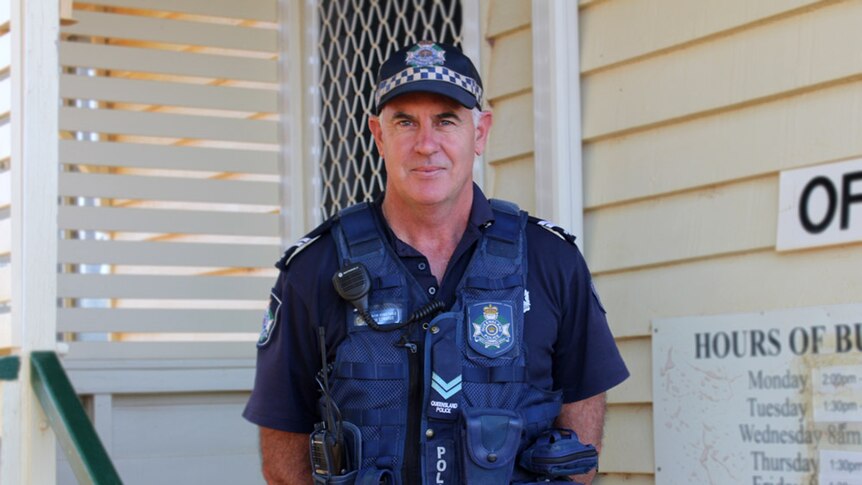 Senior Constable Rob Edwards dressed in uniform, standing  on the doorstep of the Windorah police station.