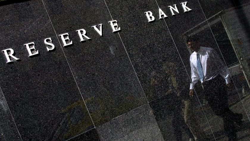 A white collar worker is reflected in the polished black granite facade of the Reserve Bank building in Sydney.