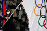 Paris Mayor Anne Hidalgo holds a flag with Olympic rings on it next to IOC president Thomas Bach at the Tokyo closing ceremony.