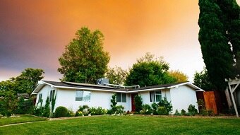 Orange sky above suburban house and lawn
