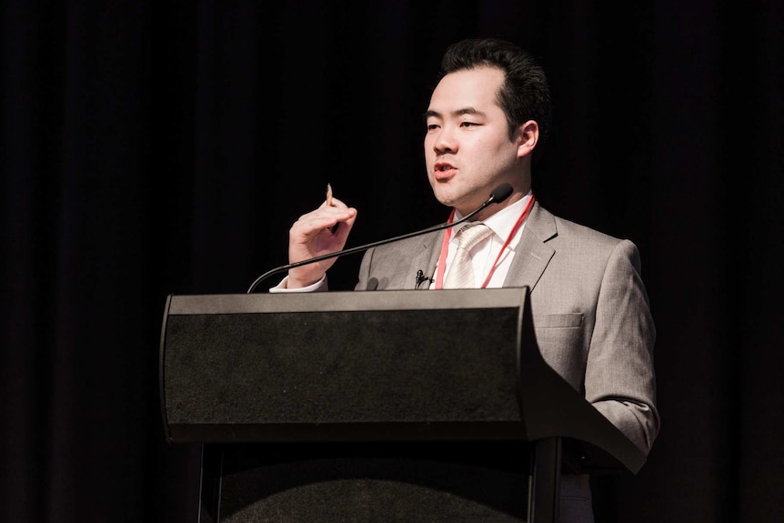 Jieh-Yung Lo speaks at a podium.