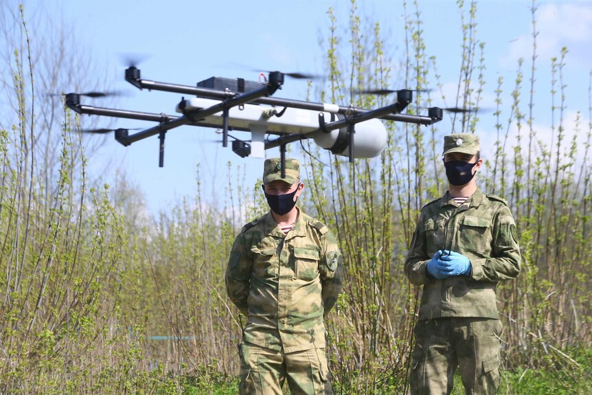 Two Russian National Guard soldiers wearing masks operate a drone in Moscow.