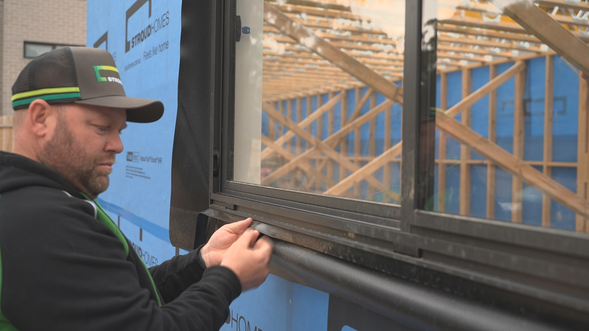Un trabajador de la construcción ajustando el marco de una ventana.