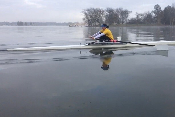 A female rower rowing on still water
