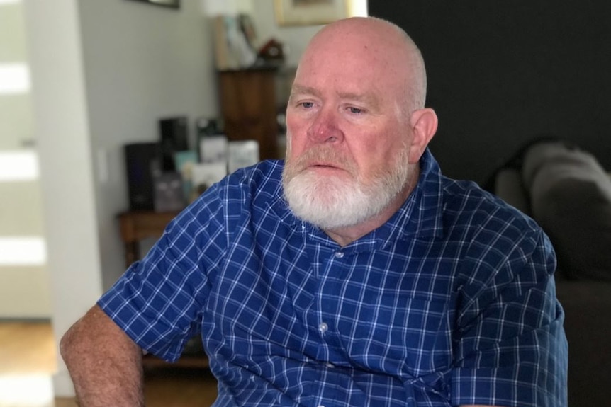 A bald man with a white beard  sitting down