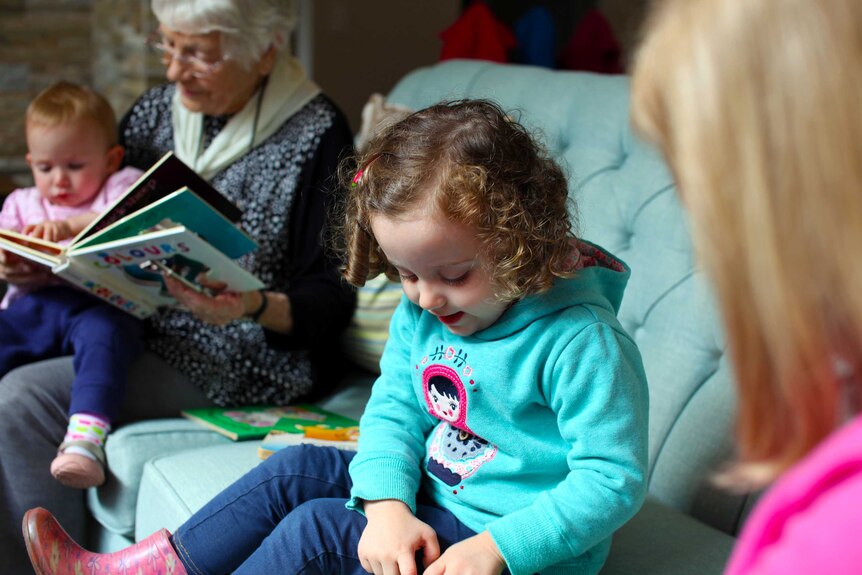 Two children and two elderly women read stories together.