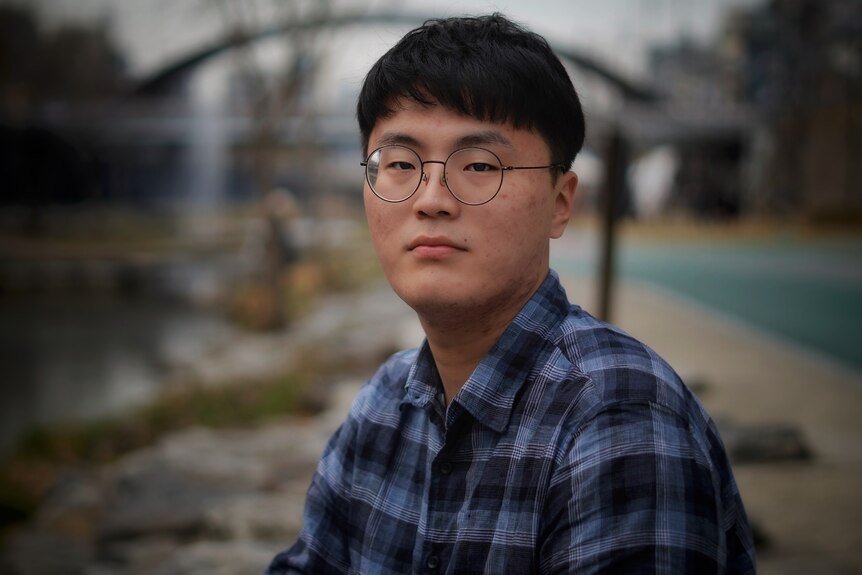 A young Asian man in wire rimmed glasses 