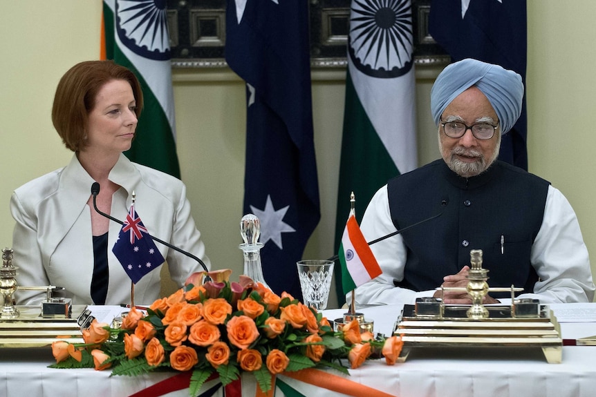 Julia Gillard watches Manmohan Singh speak after agreement signing in New Delhi.