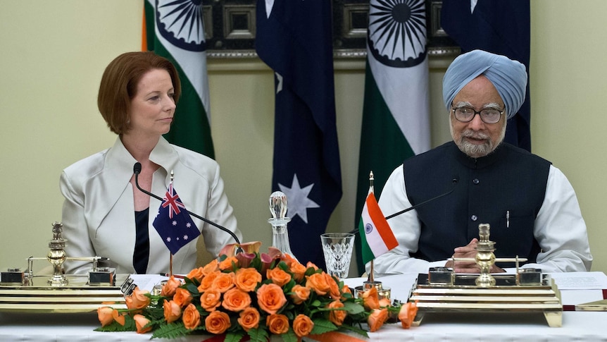 Julia Gillard watches Manmohan Singh speak after agreement signing in New Delhi.