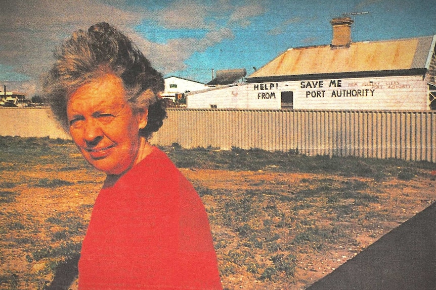 Carmel Mullally stands outside her weathered cottage sandwiched graffitied with protests against the Fremantle Port Authority