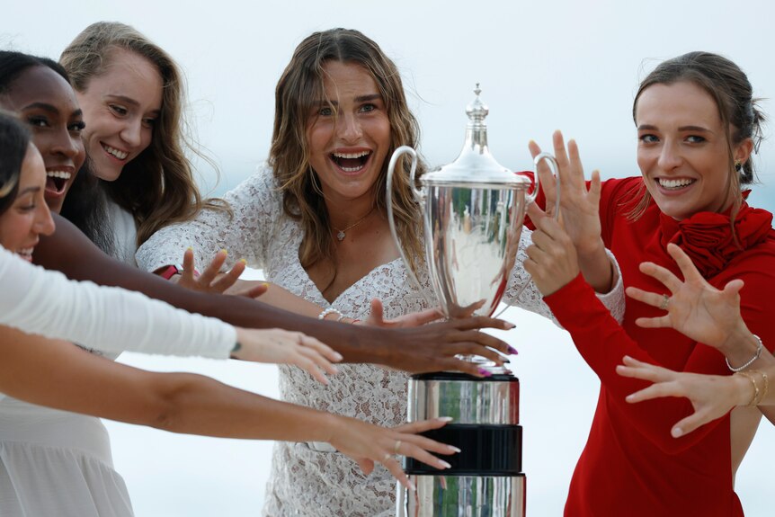 Coco Gauff, Elena Rybakina, Aryna Sabalenka and Iga Swiatek reach for the WTA Finals trophy.