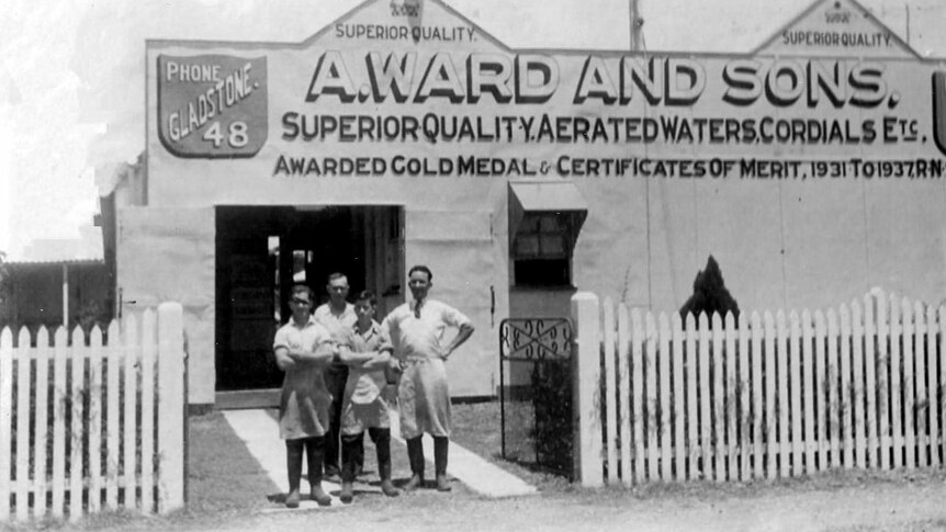 A historic photo of four people standing outside a Gladstone shed. 