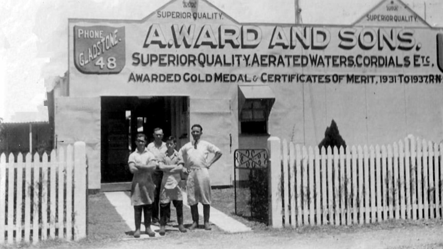 A historic photo of four people standing outside a Gladstone shed. 