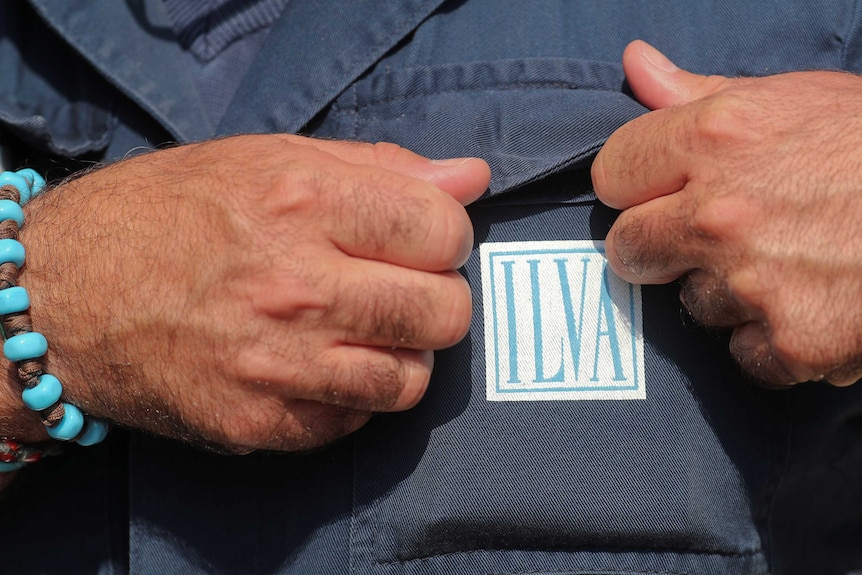 A worker adjusts his uniform outside Ilva's steel plant in Taranto.