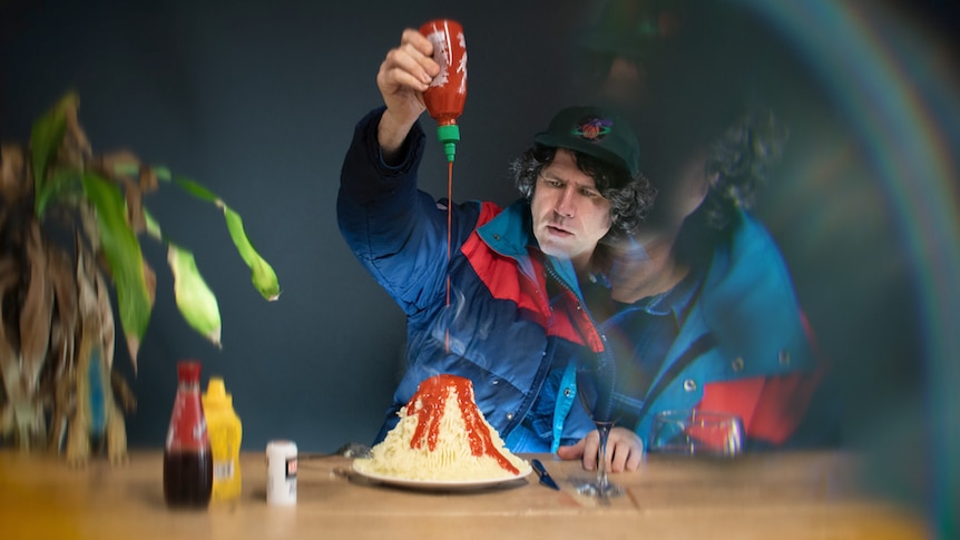 Gruff Rhys pours sriracha sauce all over a massive pile of mashed potatoes