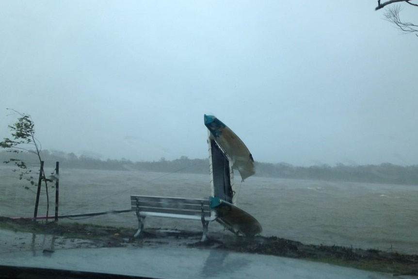 A small boat is overturned in wild weather on the Maroochy River.
