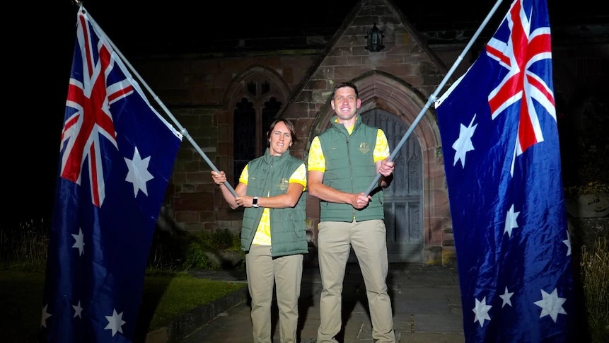 Australia's flag-bearers, Eddie Ockenden and Rachael Grinham, stand proudly waving flags in front of St Bartholomew's Church