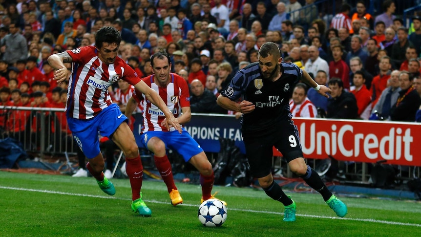 Real Madrid's Karim Benzema controls the ball as Atletico Madrid defenders try to stop him