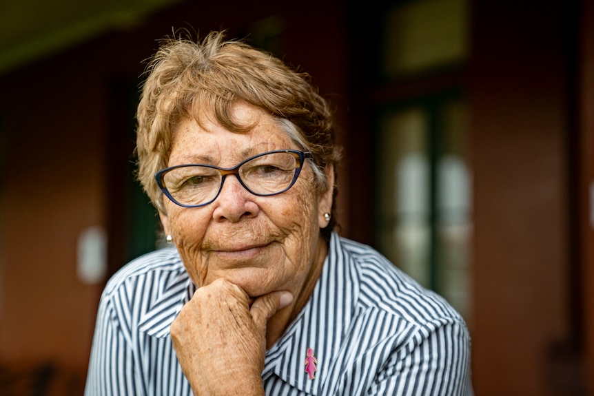 A Portrait of Aunty Barbara Simms with her hand tucked under her chin and a slight smile.