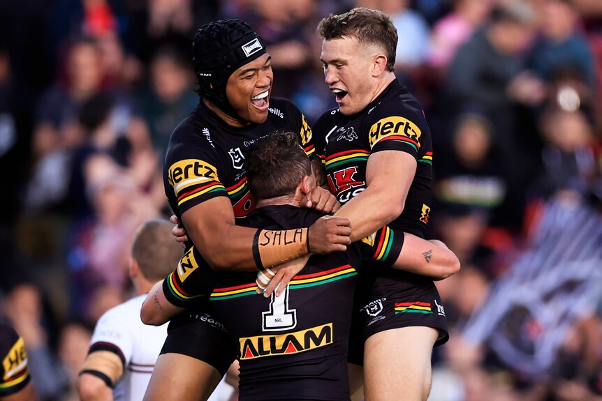 Three Penrith Panthers NRL players embrace as they celebrate a try against Manly Sea Eagles.