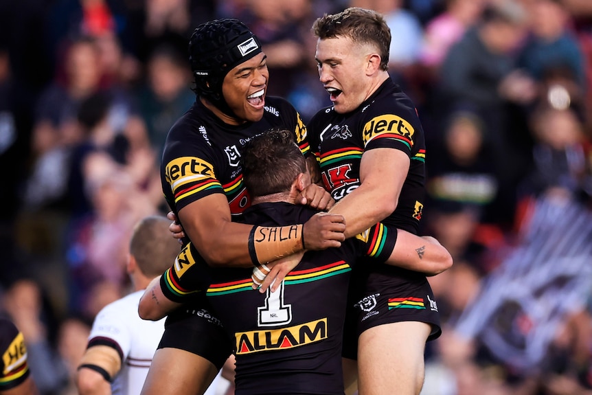 Three Penrith Panthers NRL players embrace as they celebrate a try against Manly Sea Eagles.
