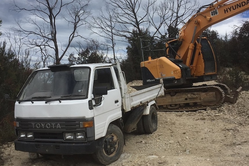 Una excavadora de 15 toneladas y un camión en un camino rural.