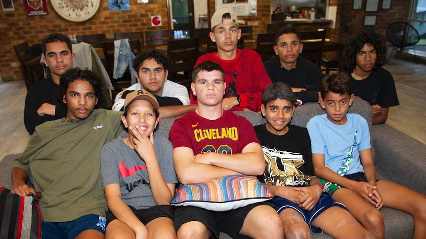 Ten boys pose for a photograph seated on and behind a sofa.