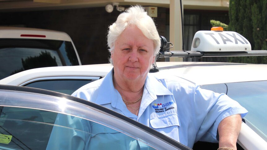 Perth taxi driver Pat Hart stands in the door of her white cab.
